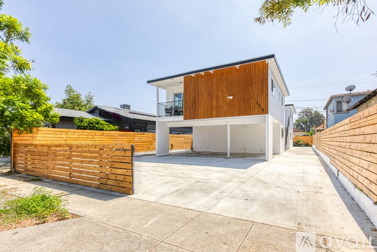 A modern house with a wooden fence and a driveway.