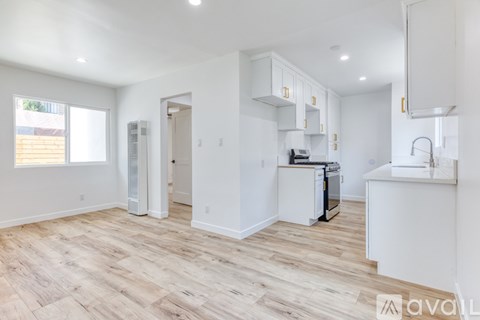 A kitchen with white cabinets and a wooden floor.