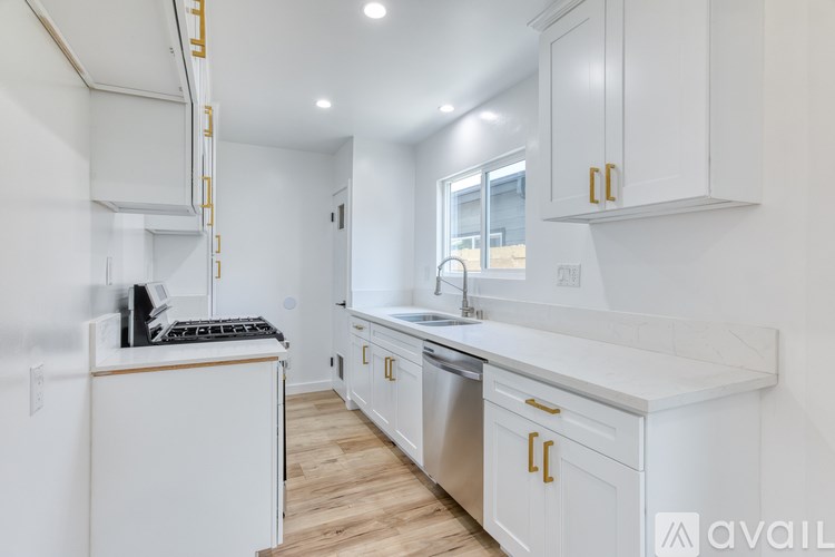 A kitchen with white cabinets and a wooden floor.