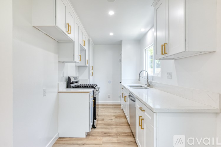 A kitchen with white cabinets and a wooden floor.