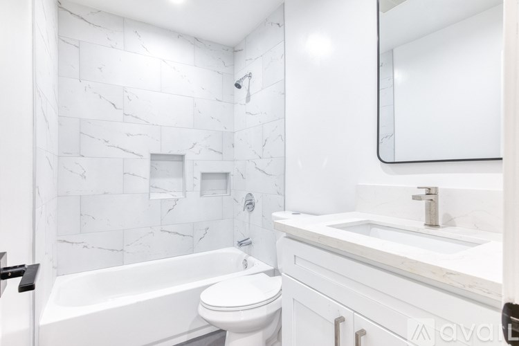 A white bathroom with a marble wall and a white tub.