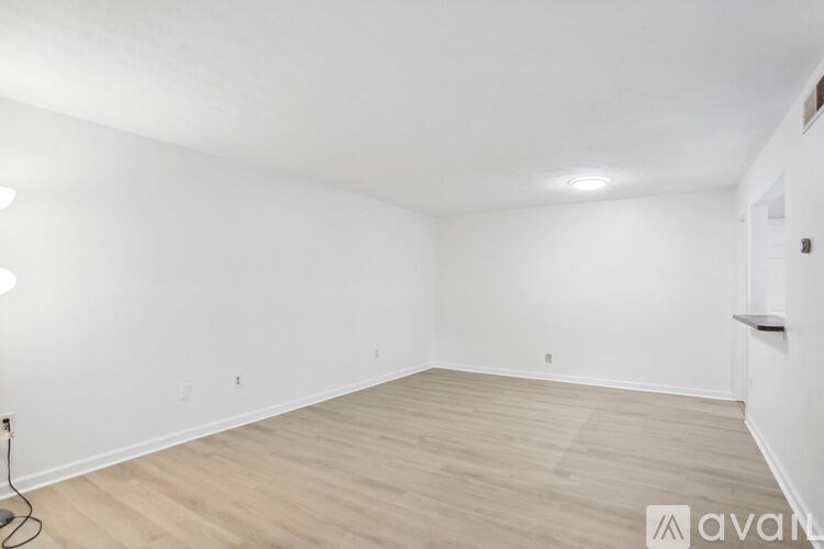 A large empty room with wooden flooring and white walls.
