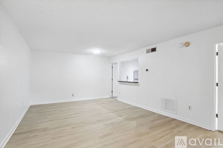 A spacious room with wooden flooring and white walls.