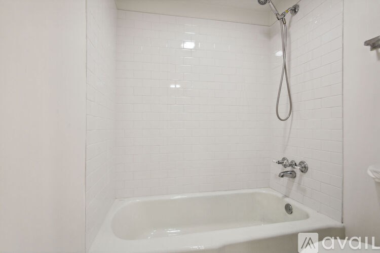 A white bathroom with a bathtub and a shower head.