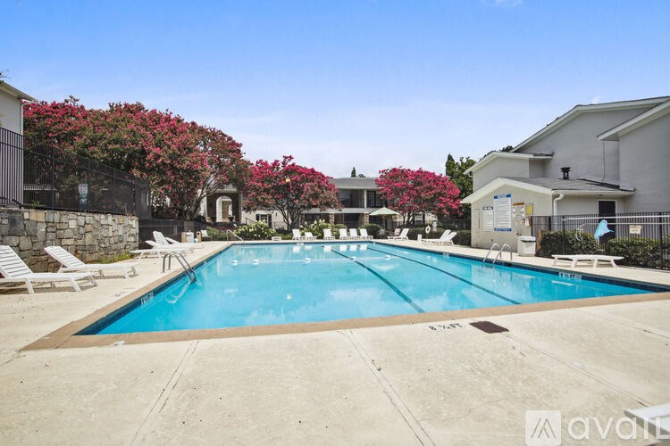 A pool surrounded by chairs and flowers.