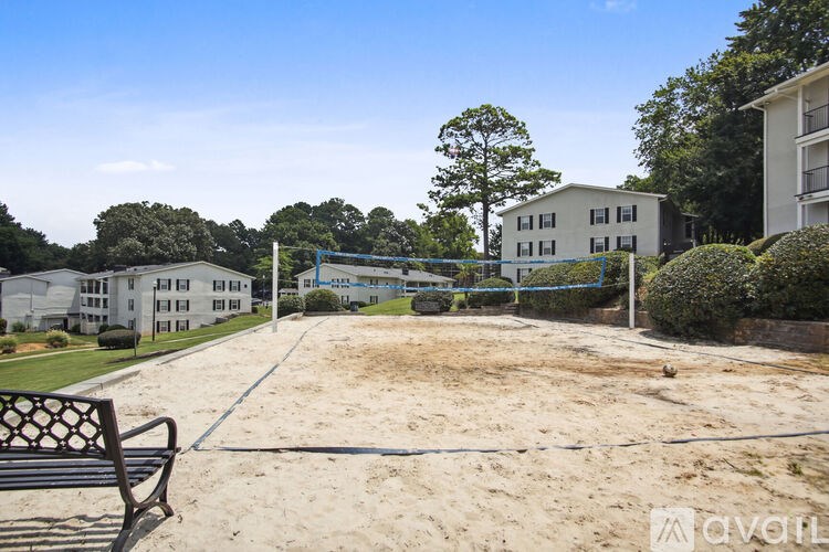 A sandy area with a bench and a tennis court in the middle of a residential area.