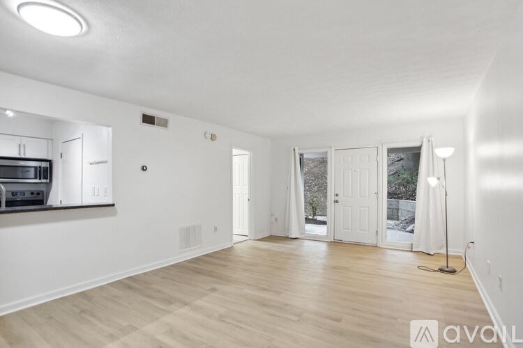 A spacious living room with wooden flooring and white walls.