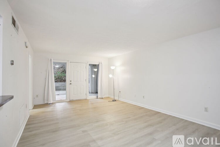 A spacious room with wooden flooring and white walls.