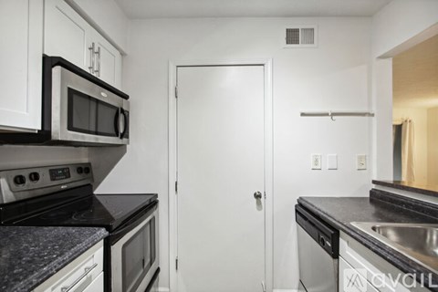 A kitchen with white cabinets and black countertops.