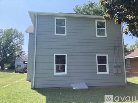 A grey house with two windows and a small porch.