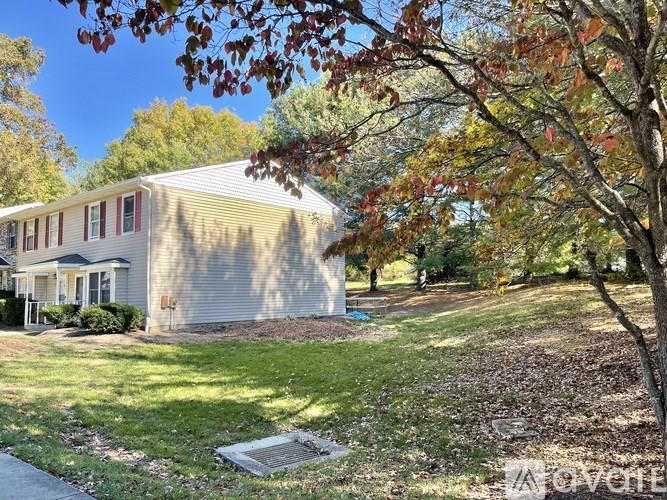 A house with a grey roof and a tree with red leaves in front.
