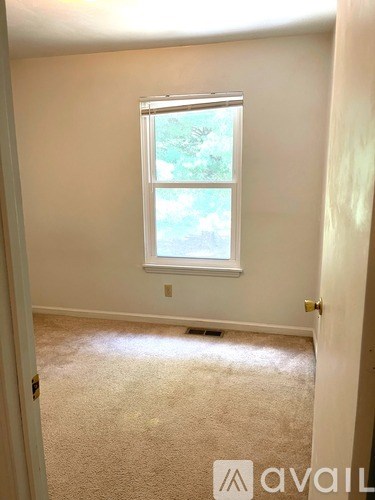 A room with a window and carpeted floor.