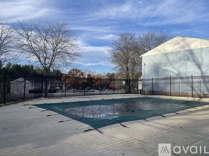 A pool surrounded by a black fence with trees in the background.