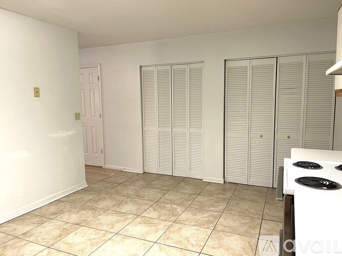 A white room with a tiled floor and a white gas stove.