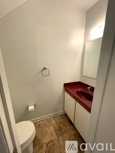 A bathroom with a toilet, sink, and mirror.