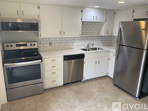 A kitchen with white cabinets and a stainless steel refrigerator.