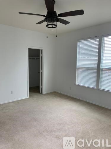 A room with a ceiling fan and a window with blinds.