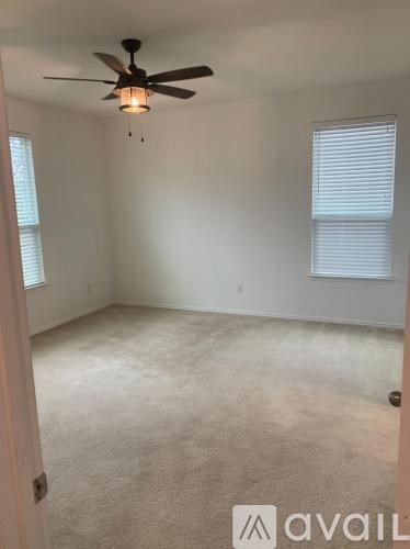 A room with a ceiling fan and carpeted floor.