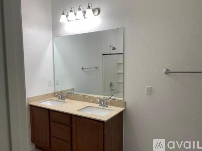 A bathroom with a double sink vanity and a mirror above it.