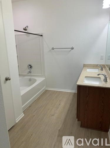 A bathroom with a tub, sink, and wooden floors.