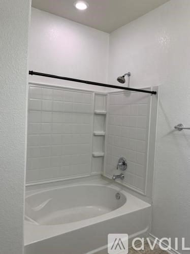 A white bathroom with a white tub and a white shower.