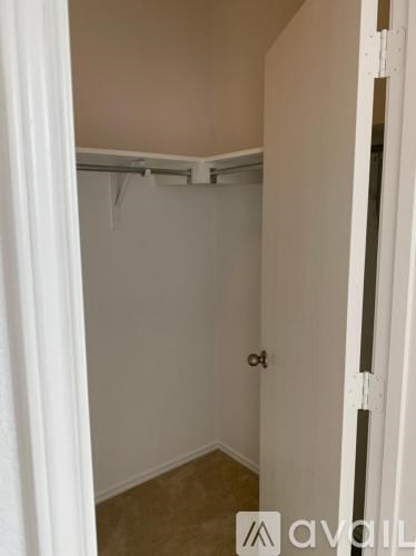 A white door is open to a small room with a brown floor.