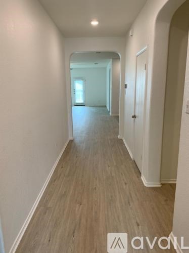 A long hallway with wood flooring and white walls.