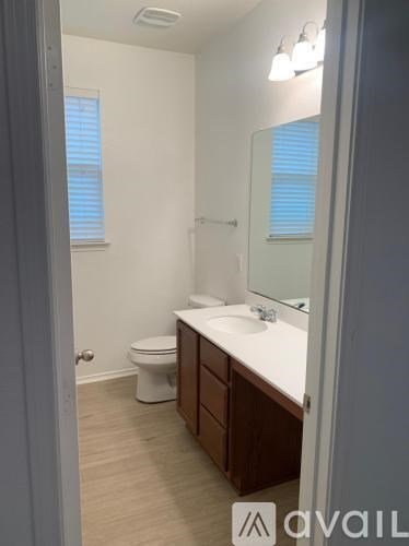 A bathroom with a toilet, sink, and mirror.