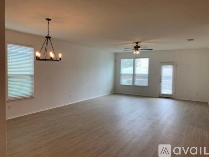 A spacious room with wooden flooring and a ceiling fan.