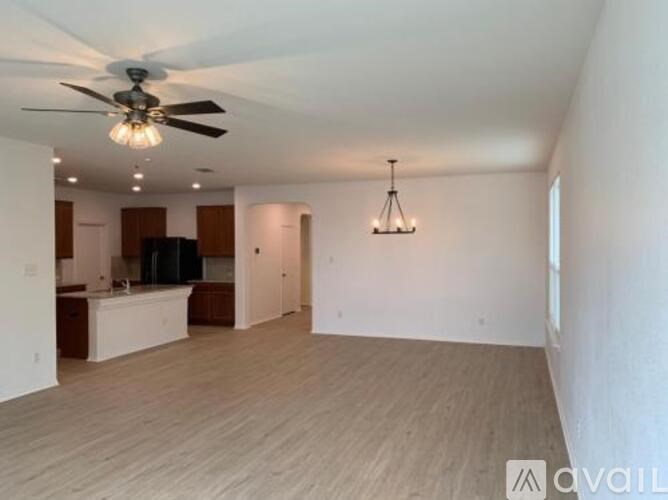 A spacious living room with a ceiling fan and hardwood flooring.