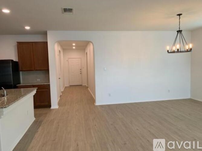 A spacious room with wooden flooring and a chandelier hanging from the ceiling.