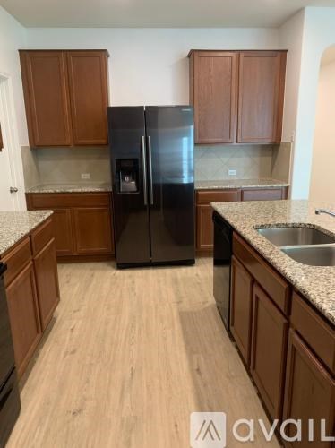 A kitchen with wooden cabinets and a black refrigerator.