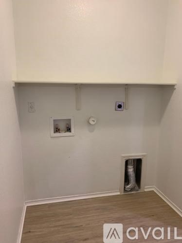 A room with a white wall and a white ceiling with a small window and a vent.