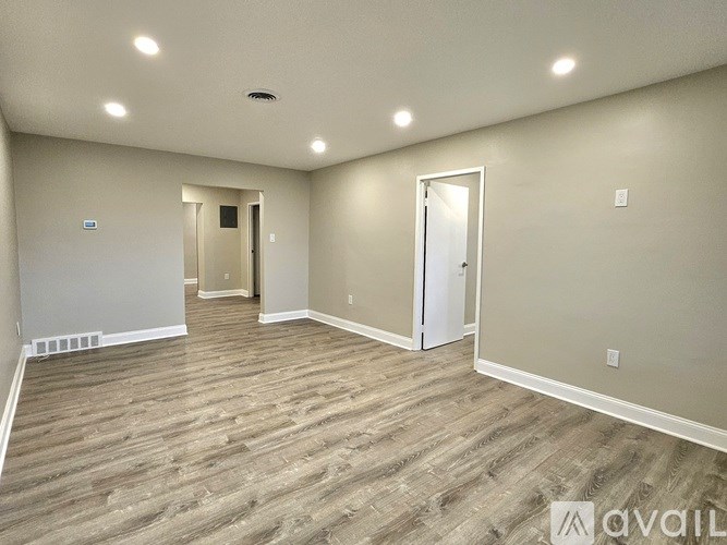 A spacious room with wood flooring and white walls.