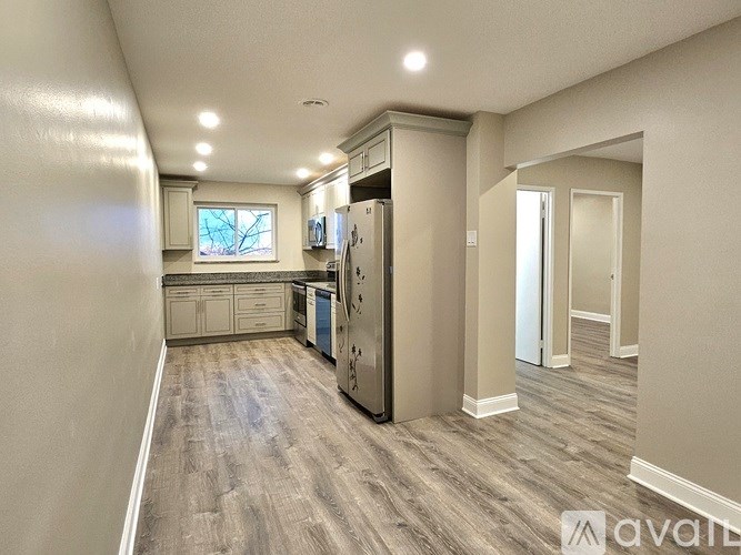 A kitchen with a refrigerator, cabinets, and a window.