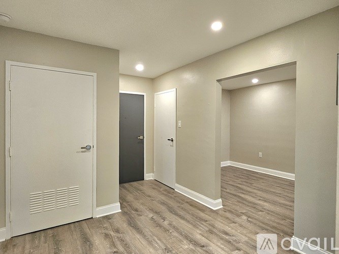 A room with a white door, a black door, and a white door with a window.