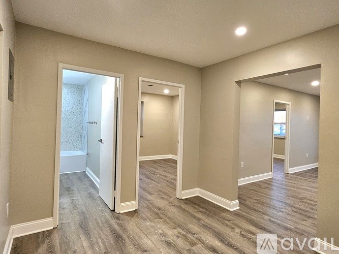 A spacious room with wood flooring and white walls.