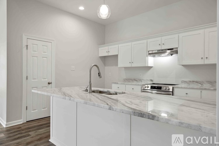A kitchen with white cabinets and a marble countertop.