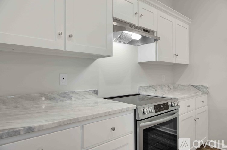 A kitchen with white cabinets and a marble countertop.