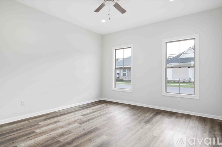 A room with a ceiling fan and two windows.