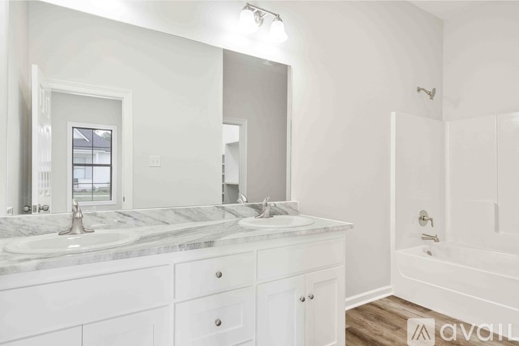 A white bathroom with a marble countertop and a large mirror.
