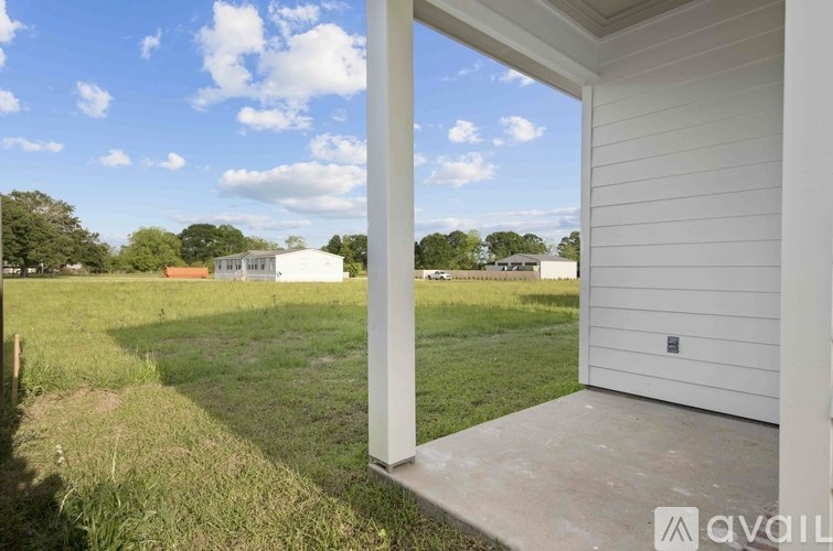A white house with a porch and a view of a field.