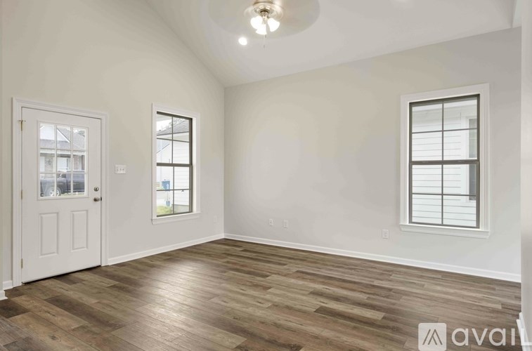 A room with wooden flooring and two windows.