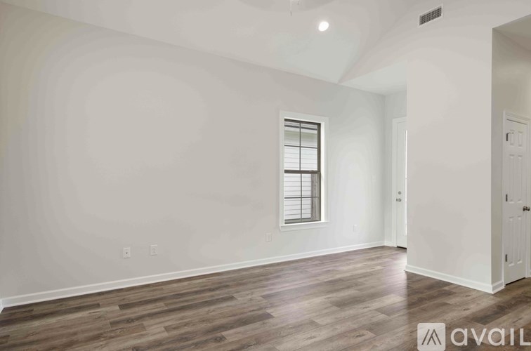 A room with wooden flooring and a window with blinds.