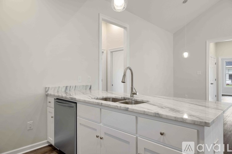 A kitchen with white cabinets and a marble countertop.