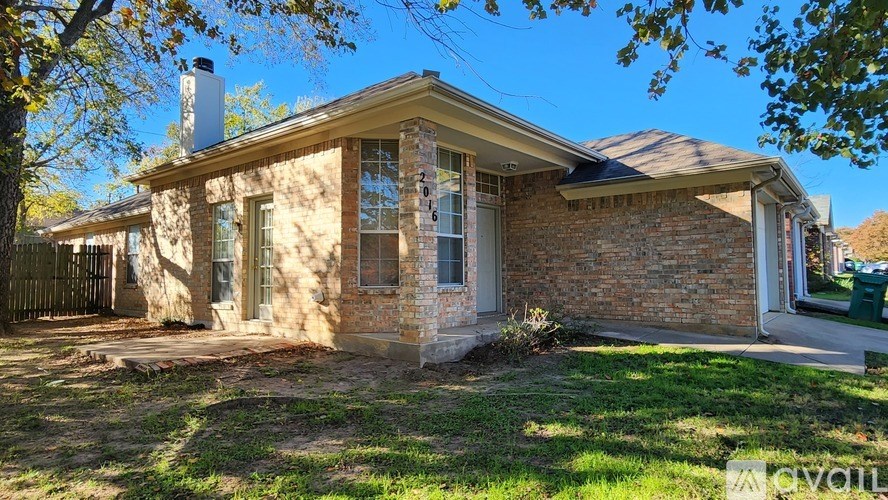 A brick house with a chimney and a tree in front.