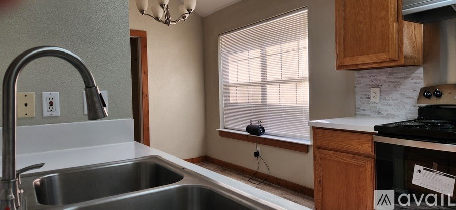A kitchen with a stainless steel sink and wooden cabinets.