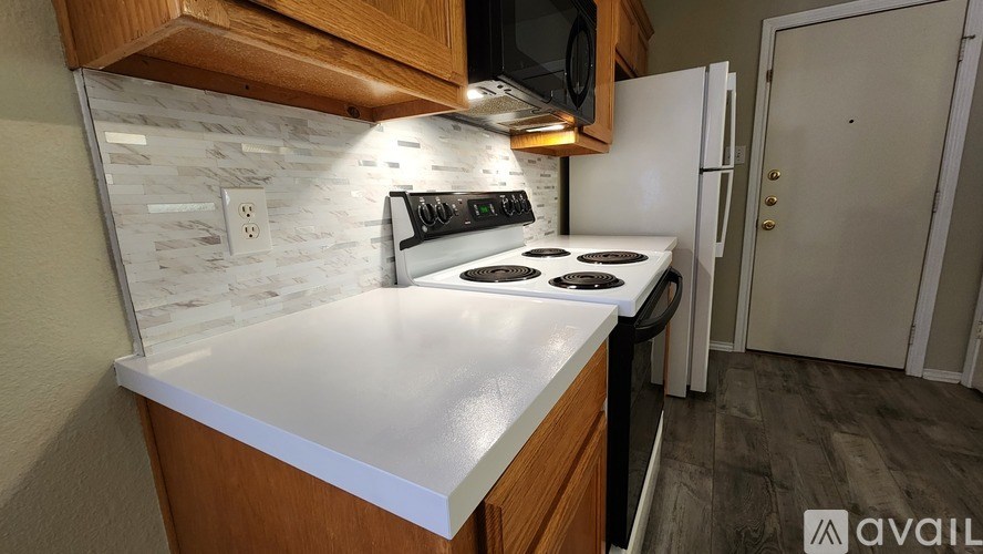 A kitchen with a white countertop and a white stove top oven.