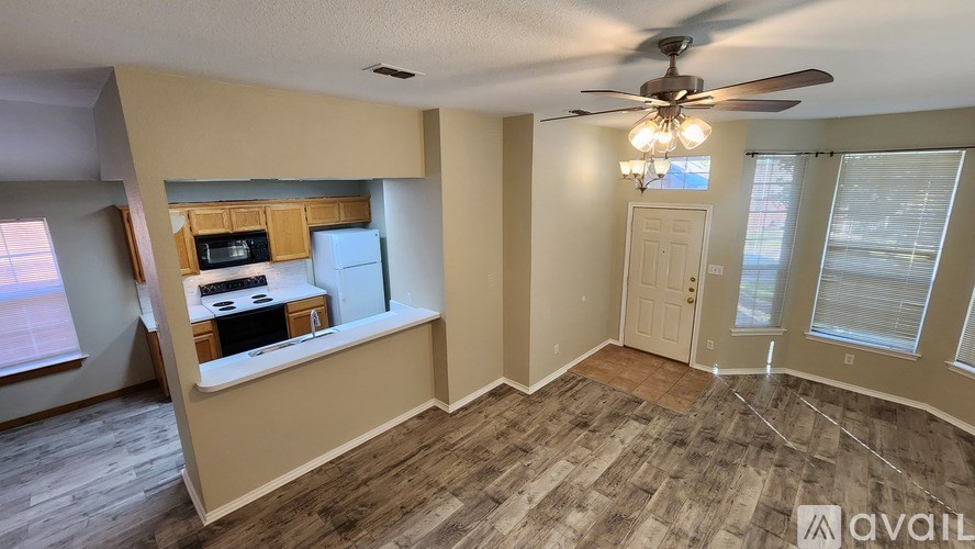 A room with a ceiling fan and wood flooring.