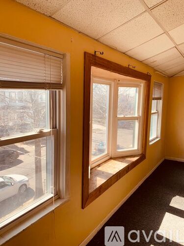 A room with yellow walls and a window overlooking a parking lot.